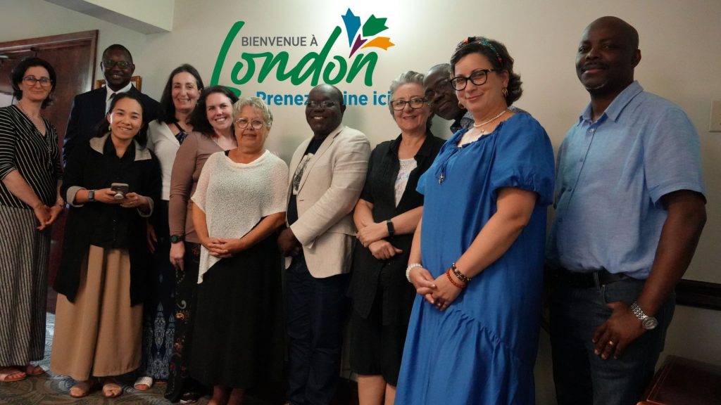 Photo des membres du Conseil consultatif communautaire de la CFA London avec le logo Bienvenue à London - Prenez racine ici derrière